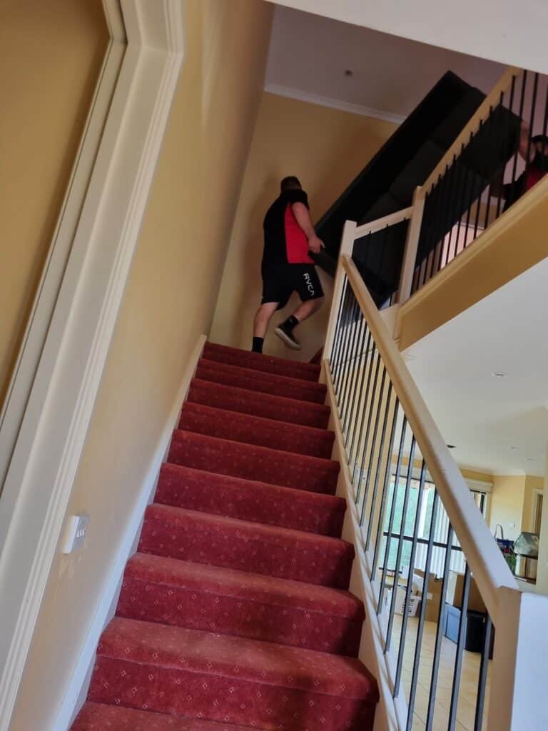 Removalists Carrying Couch Up Stairs